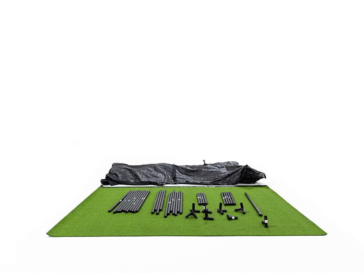 Animated GIF showcasing a front-facing perspective of a full SKYTRAK indoor golf simulator studio enclosure, featuring a bright white impact projection screen framed by black light-blocking fabric wall panels and a green synthetic turf hitting floor mat, isolated on a white background.